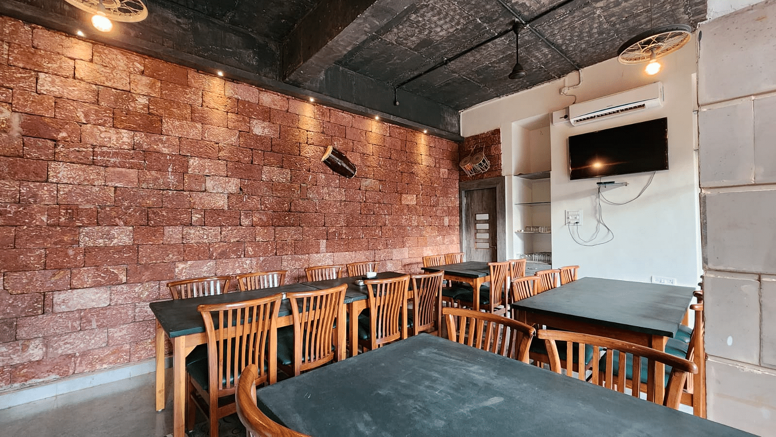 There are tables and chairs around them with warm lighting and a wall-mounted TV at SeaFort Beach Resort