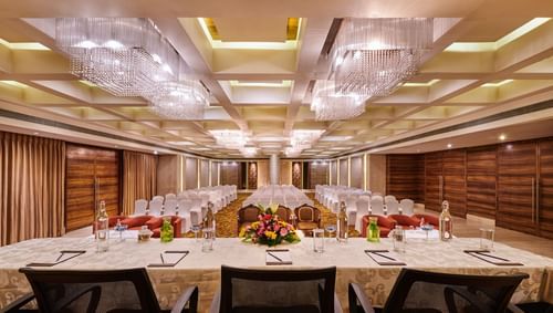 Event hall at The Pride Premier Nagpur featuring a conference table and chairs for the guests and there are several chairs in front of the table.