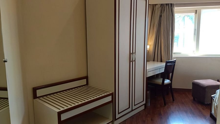 An image showcasing a room with a wardrobe, work desk, chair, and a shoes and luggage rack - Ras by Treat Resorts