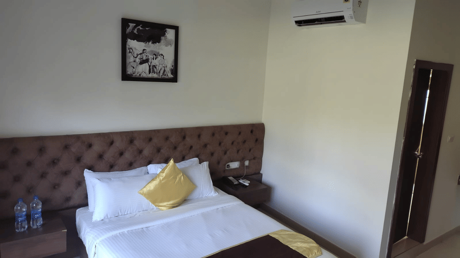 The Standard Room at Cholaa Dynasty, Kumbakonam with a double bed, wall artwork, and air conditioner.