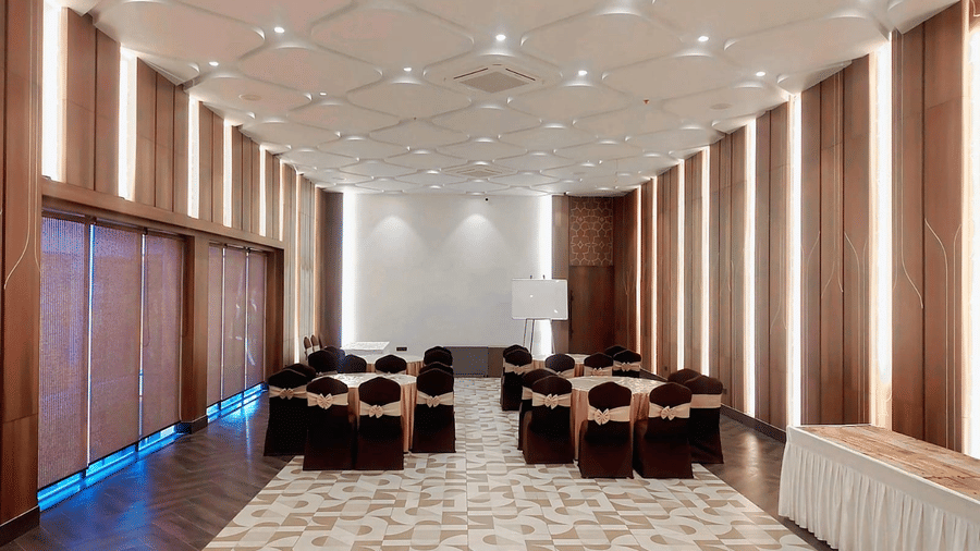 Elegant Arohanika hall with round-table seating, decorative ceiling lighting, presentation area, and modern interiors suitable for corporate meetings and weddings at Hotel Sonar Bangla Ajodhya Hills.