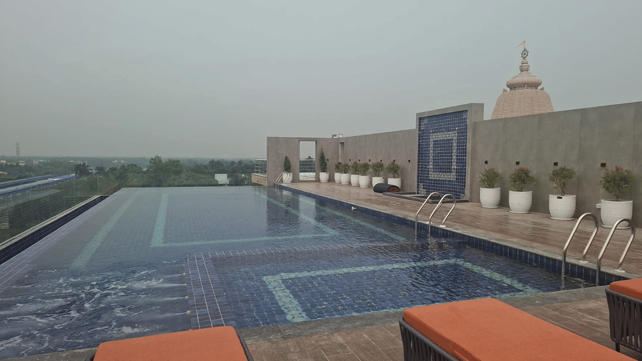 Infinity-style rooftop swimming pool at Le ROI Digha Hotel, West Bengal, with deck chairs and open surroundings.