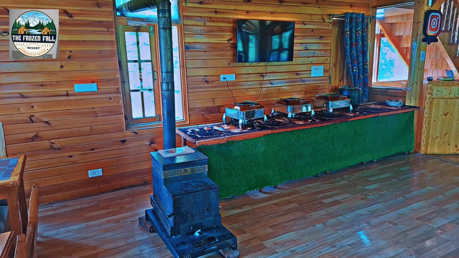An indoor buffet counter at Dawat e Drung by FrozenFall Resort, Drung, Tangmarg, with dishes arranged on a long table in a wood-panelled room.