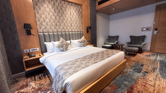 A modern bedroom featuring a king-sized bed with a patterned headboard and vibrant multicoloured carpeting at Ananta Express, Katra.