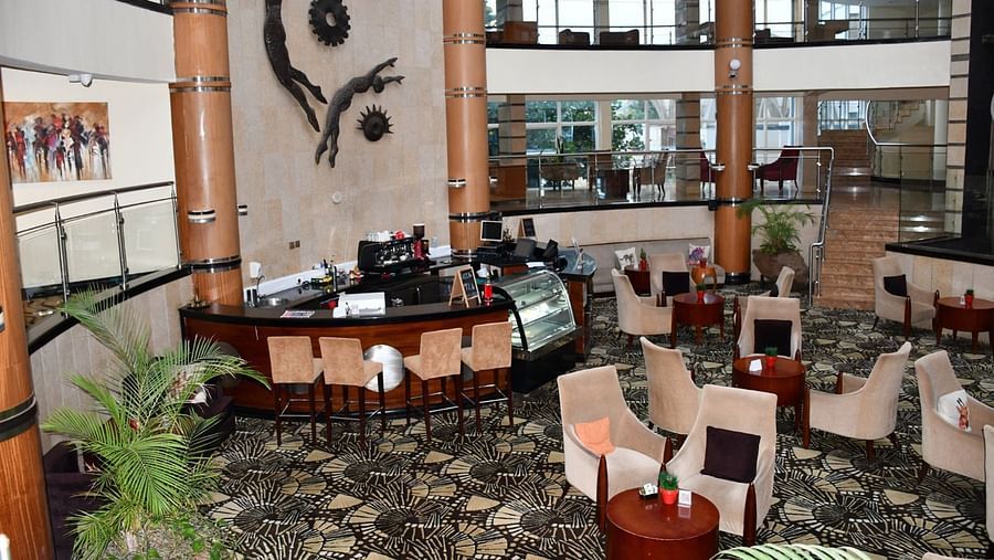 Lounge with tables, chairs, and a view of an atrium at The Boma Nairobi.