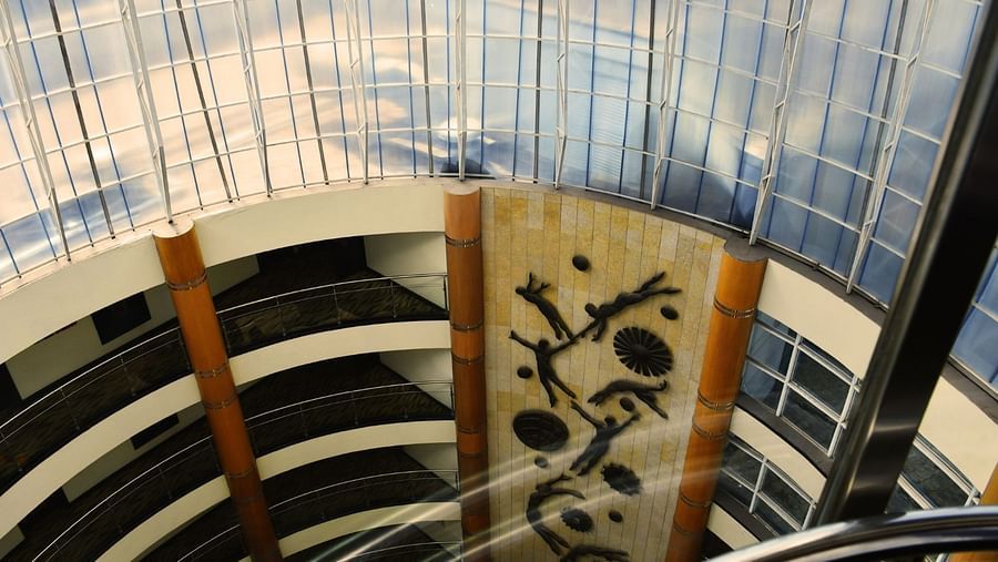 Upward view of central atrium with sweeping glass roof and patterned wall art at The Boma Nairobi.