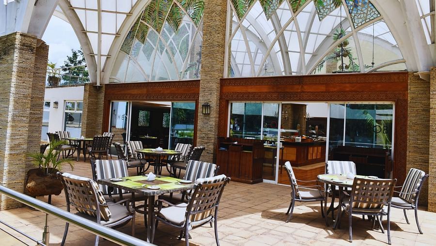 Outdoor terrace dining area with tables and chairs at The Boma Nairobi. 