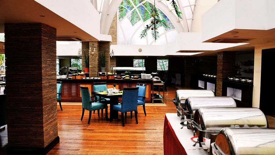 Bright restaurant with turquoise chairs, wooden floors, table settings at The Boma Nairobi.
