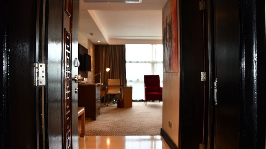 A corridor leading to a well lit room with chairs and floor to ceiling window at the Boma Nairobi. 