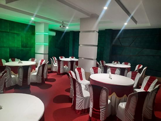 A banquet hall with a bunch of well decorated tables and chairs - Mysore Gate Hotel Bangalore