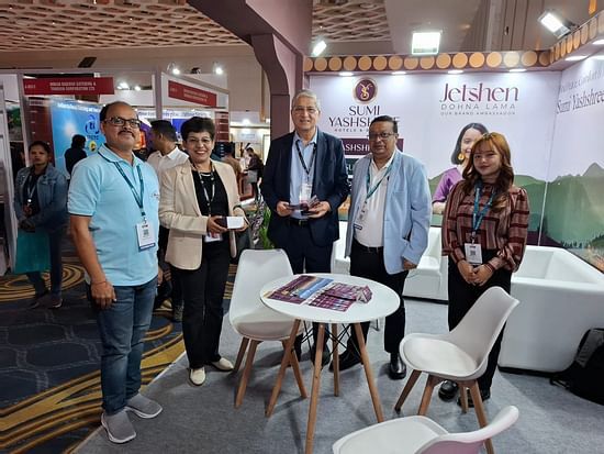 Group photo at the Sumi Yashshree Hotels & Resorts booth, featuring team members and visitors engaged in a professional event setting.