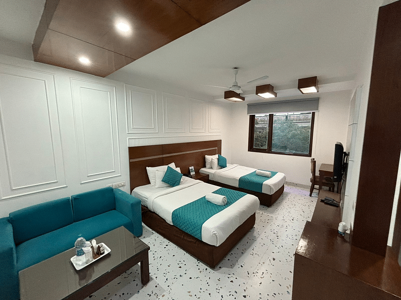 A hotel room with two beds, a sofa, and a coffee table - Asian Suites IFFCO Chowk Metro Station, Gurgaon. 