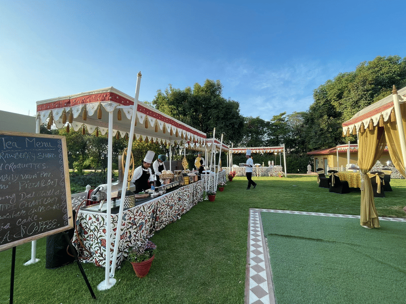 Outdoor event setup with white tents and seating on a green lawn at Heritage Village Resorts & Spa, Manesar.