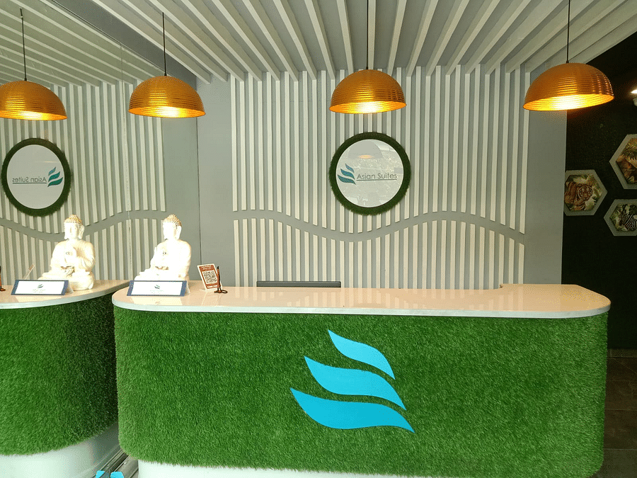 A modern reception area with a textured wall and two circular logos - Asian Suites IFFCO Chowk Metro Station, Gurgaon.