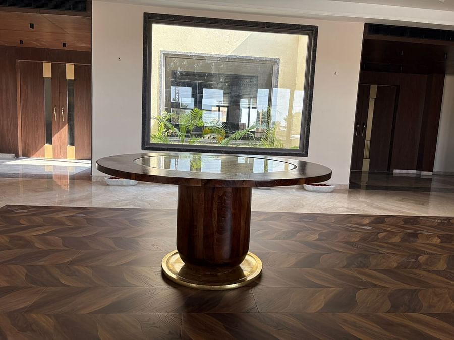 An image of a huge centre table with wooden and glass finish at a lobby - Pride Hotels Group