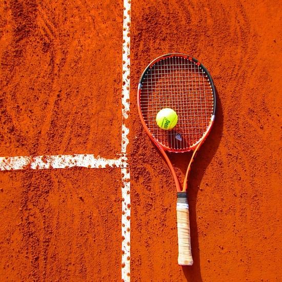 A Tennis racquet and a Tennis ball on a grainy floor