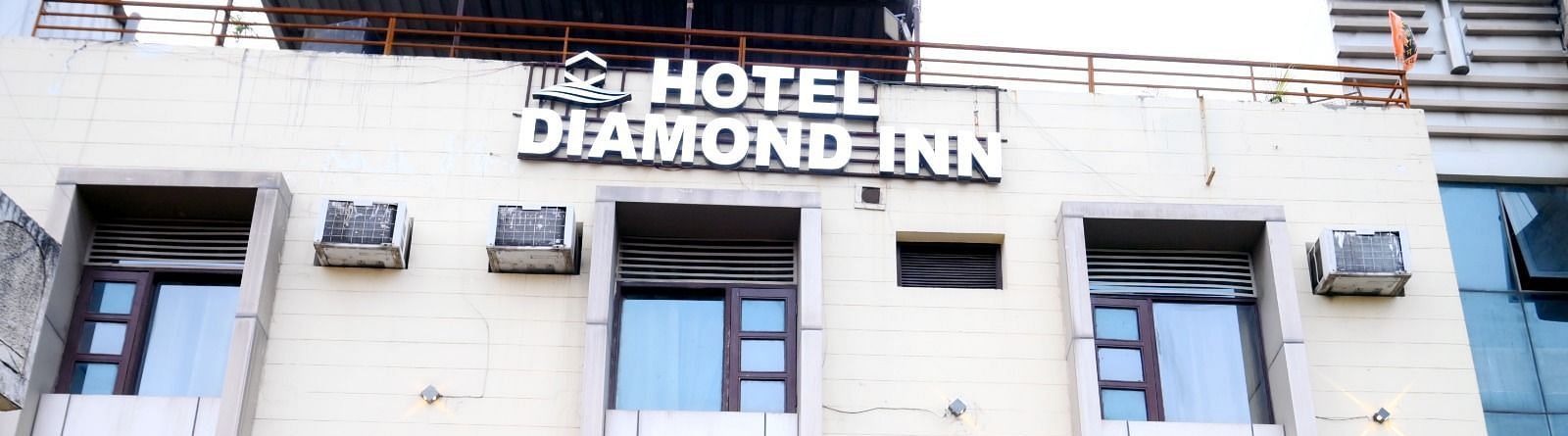 A well-lit exterior of Hotel Diamond Inn, showcasing the building façade with windows and air conditioning units - Hotel Diamond Inn, Chandigarh