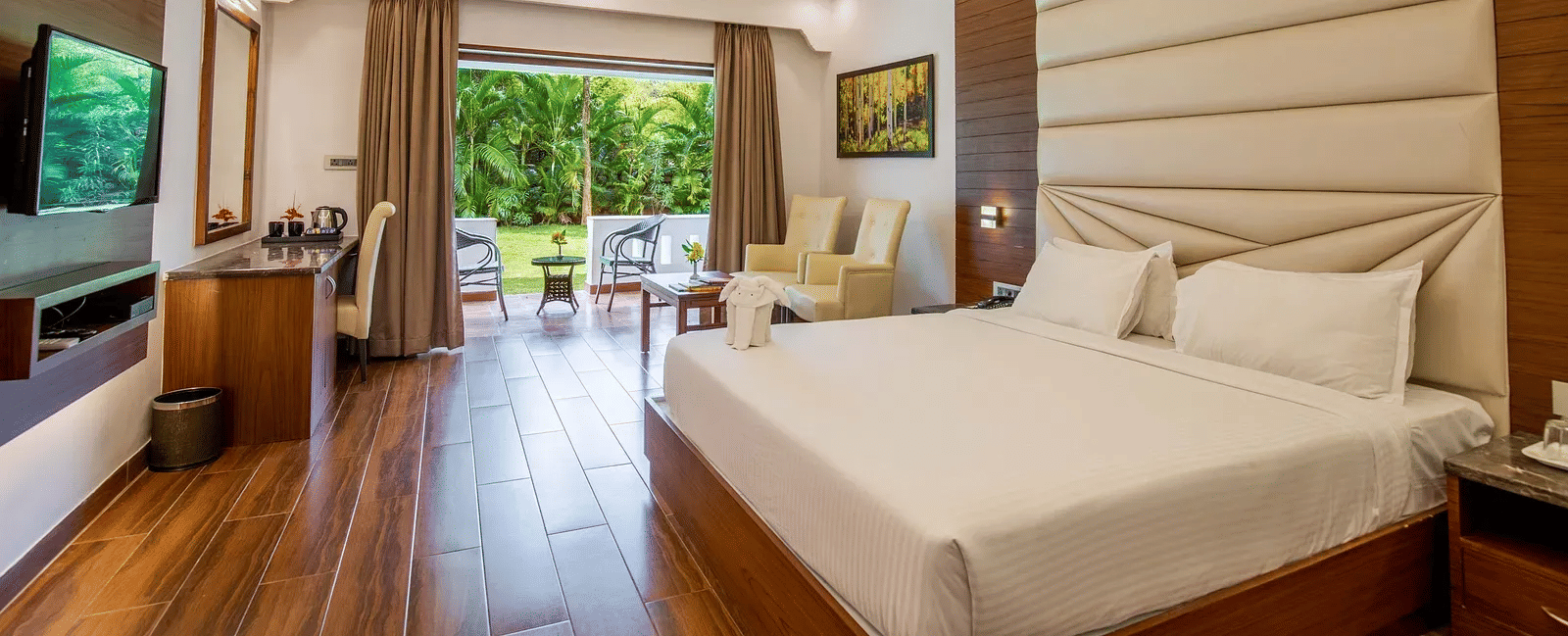 A double bed room with wooden floors, seating area, window and a door with a scenic view outside at Avana Resort