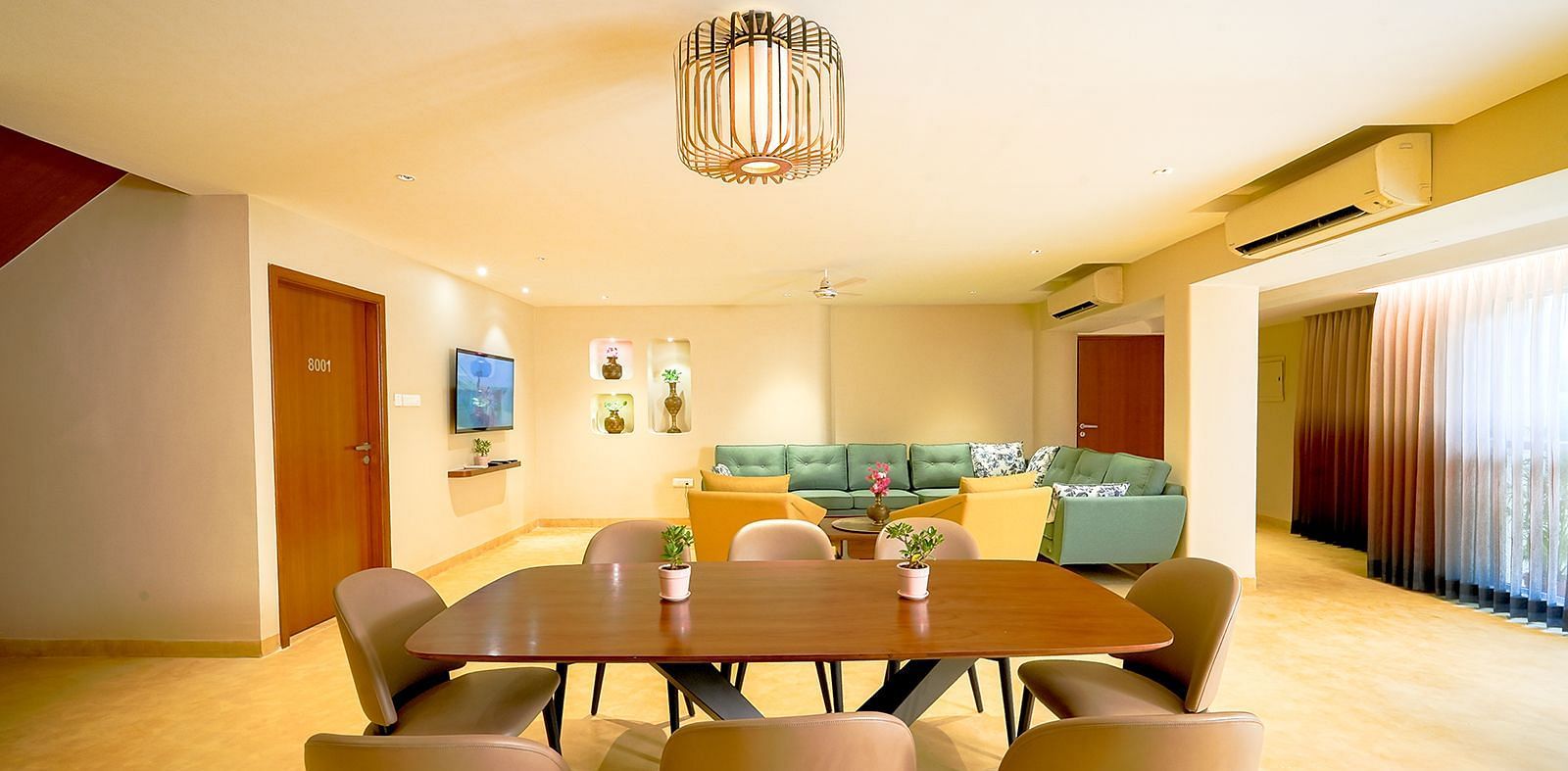 Modern dining area at Vasundhara Villa featuring a large dining table, ambient lighting, and family-friendly space.