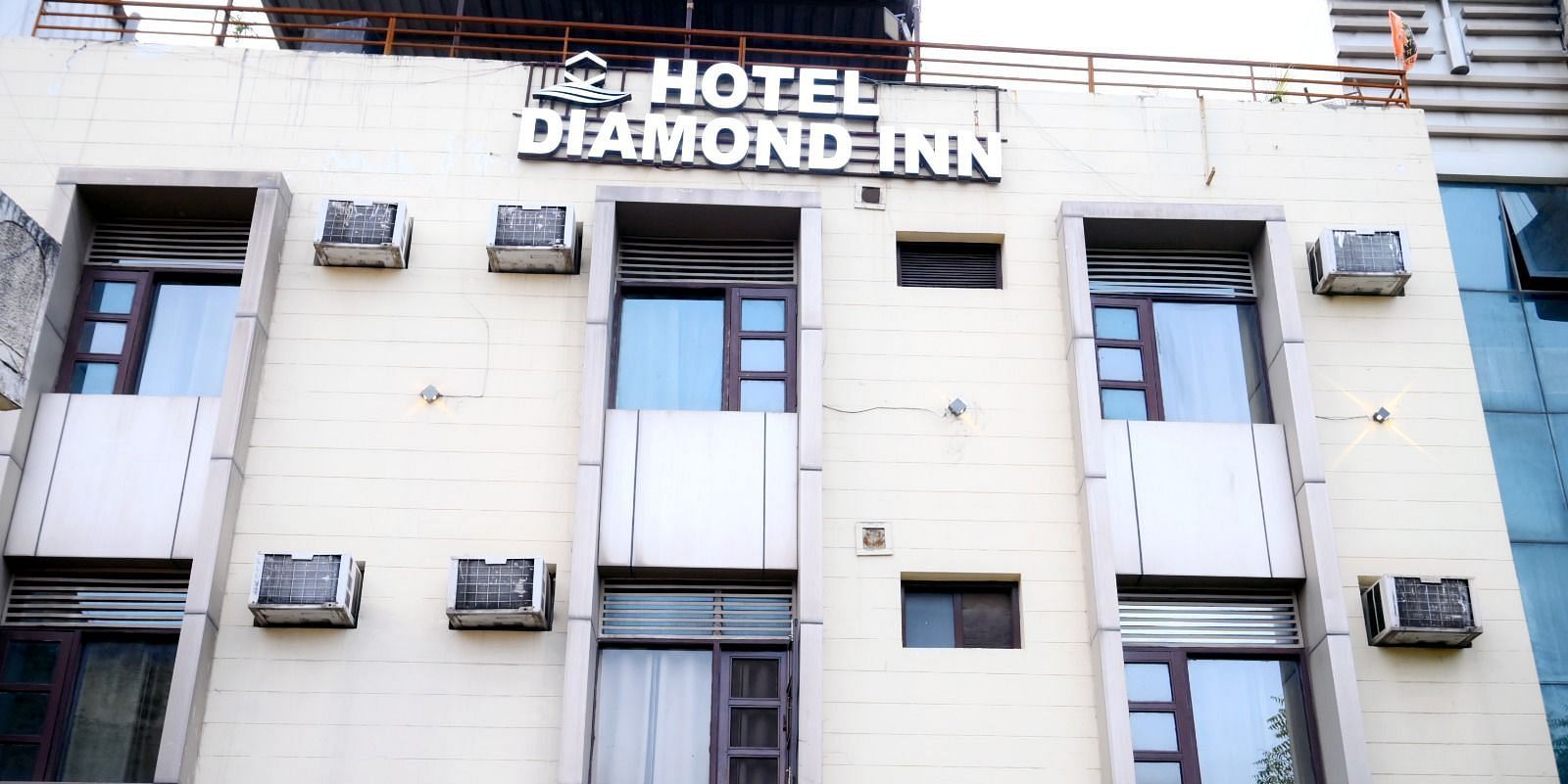 A well-lit exterior of Hotel Diamond Inn, showcasing the building façade with windows and air conditioning units - Hotel Diamond Inn, Chandigarh