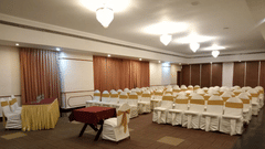 A banquet hall with rows of chairs and tables arranged at best resort in Bangalore | Ramanashree California Resort