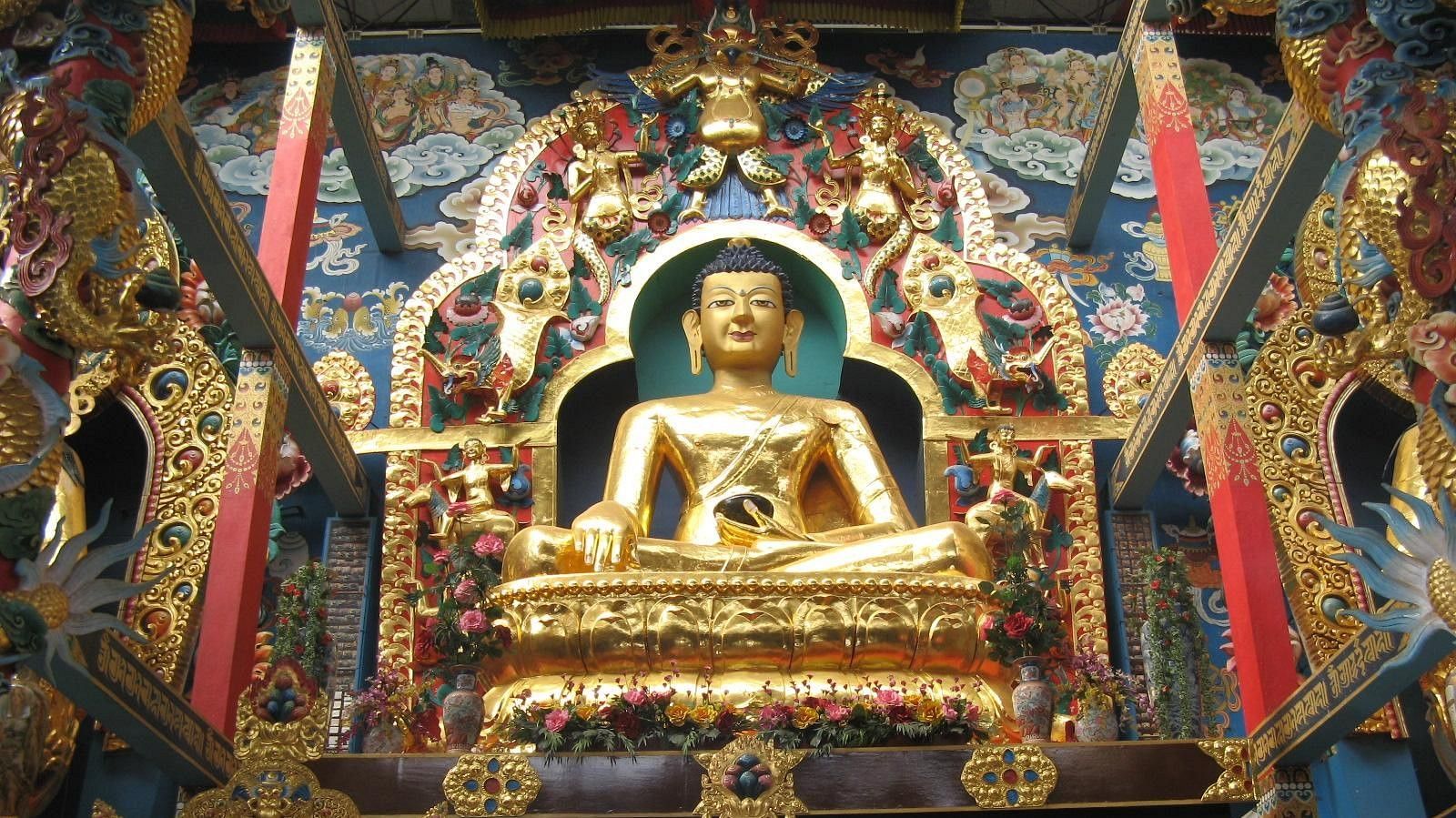 Ornate golden Buddha statue with colorful decorations in a temple.
