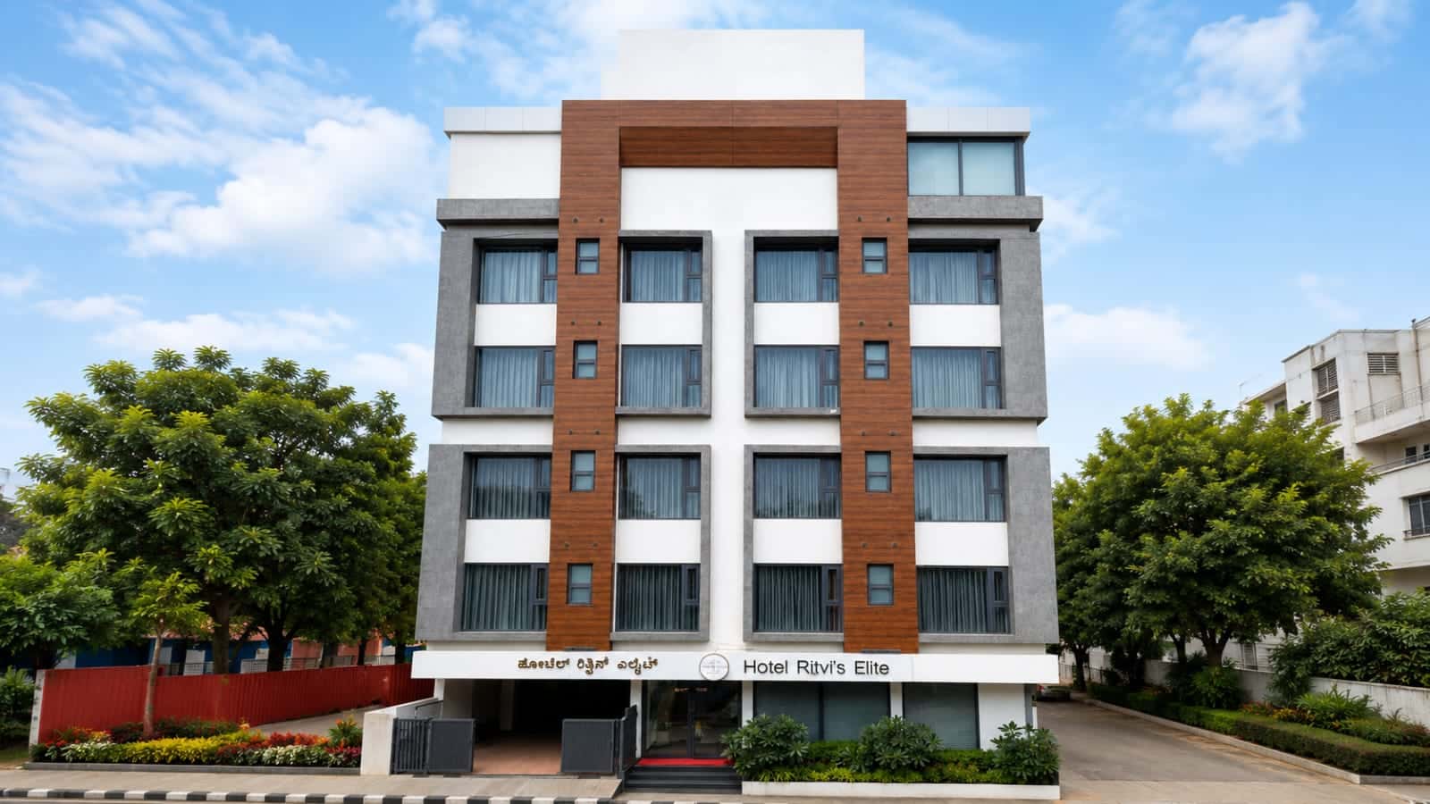 Hotel Ritvi's Elite by day, the four-storey facade in white and timber-brown panels with the hotel signage above the entrance