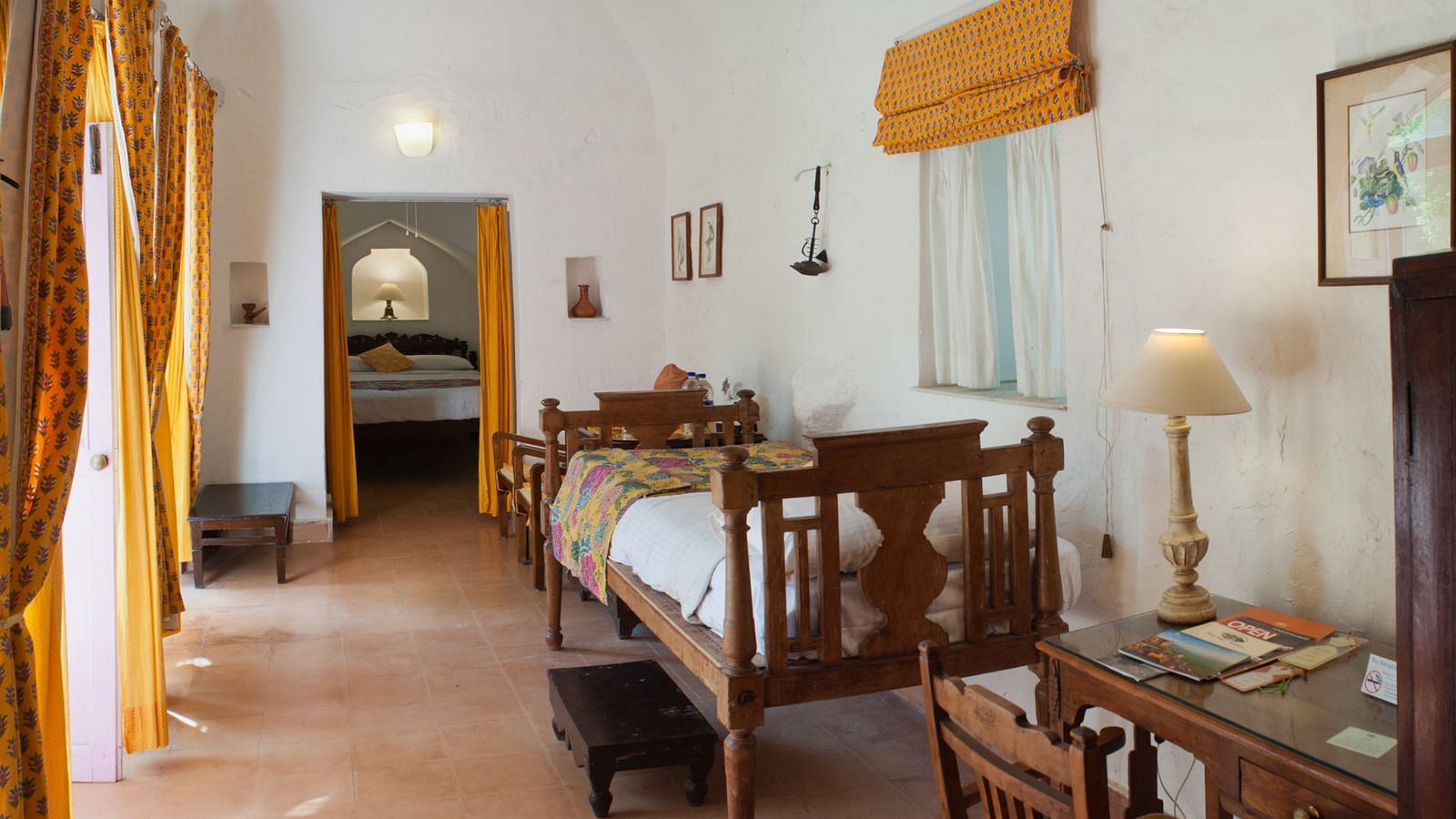 Hill Fort Kesroli 14th Century Alwar - interior view of the Deppika Mahal room with a single bed, lamp and orange decor