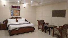Suite Rooms at VITS Select, Bharuch featuring a double size bed, a bedside table, and a seating area with chairs and centre table.