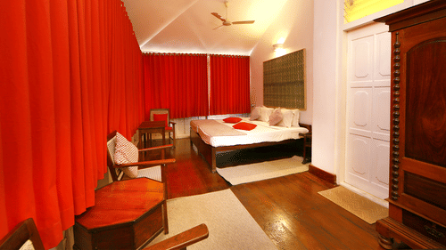 The Tower House - The Breakopt room with red & white theme that features a queen size bed along with a wooden wardrobe, a workdesk and a tea table with chair