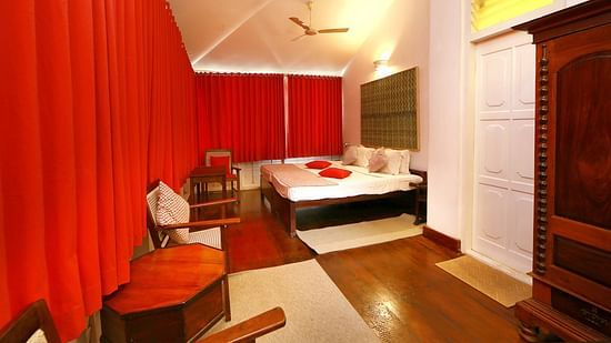 The Tower House - The Breakopt room with red & white theme that features a queen size bed along with a wooden wardrobe, a workdesk and a tea table with chair