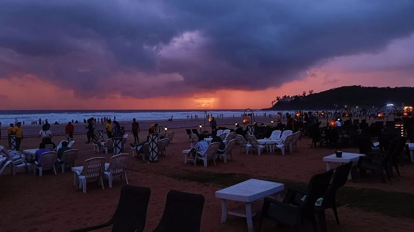 Vibrant sky seen over a beach that is full of people.