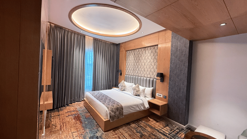 A modern bedroom with a king-sized bed, integrated wooden furniture, and warm ambient lighting at Ananta Express, Katra.