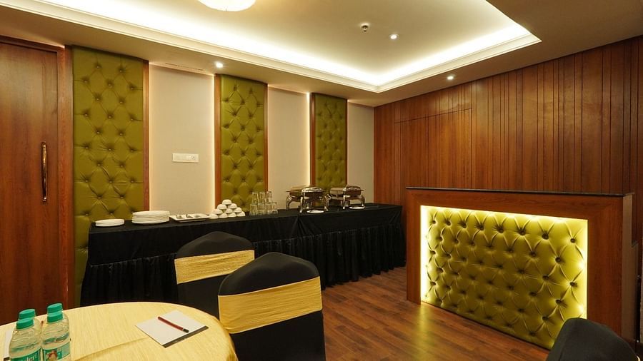 Bright meeting room with a large rectangular wooden table, ergonomic black chairs, floor-to-ceiling windows, and minimalist white walls – Magnus Nexstar Suites, Kalyani Nagar