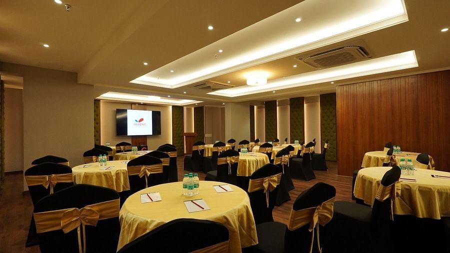 Modern boardroom featuring a long polished wooden table, high-back black chairs, soft ambient lighting, and wood-panelled walls – Magnus Nexstar Suites, Kalyani Nagar