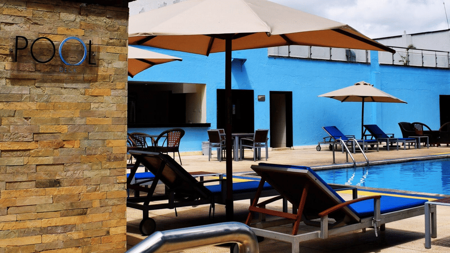 Outdoor swimming pool with sun loungers and umbrellas at The Boma Nairobi.