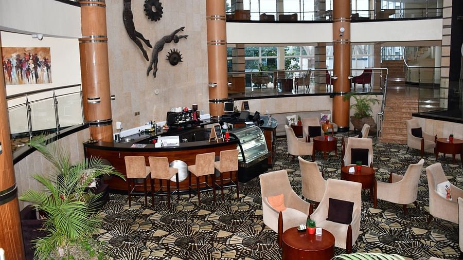 Lounge with tables, chairs, and a view of an atrium at The Boma Nairobi.