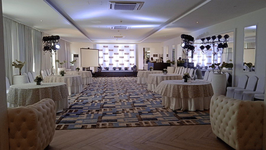 The Mansion House resort event hall with stage, purple lighting, patterned carpet, and rows of chairs, arranged for a formal seminar, presentation, or special occasion gathering.