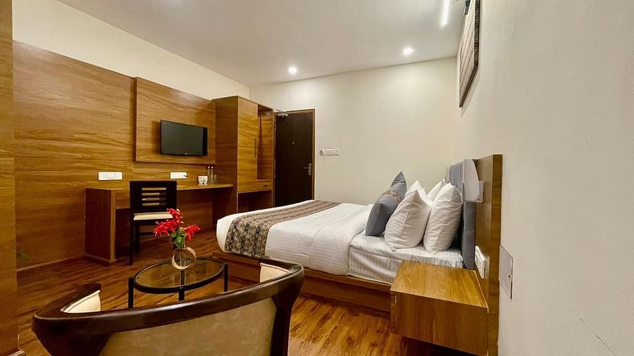A side view of a room that has a bed, teapoy, TV on the wall, and wooden desks | Voyage The Royal Retreat, Gangtok