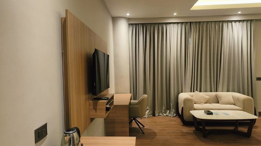 Superior Forest View Room at Silver Sand Sea Princess Beach Resort with wall-mounted television, work desk and chair, cream-coloured sofa, coffee table, and full-length curtains creating a warm, elegant setting
