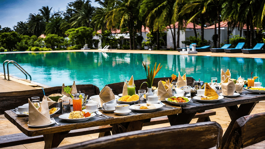 Deck Area with a beautifully set breakfast table overlooking the pool and lush palm trees at Chariot Beach Resort, perfect for relaxed dining.