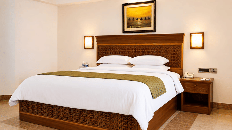 Executive Deluxe Room with a king bed, wooden headboard, and warm ambient lighting at Chariot Beach Resorts, offering a cozy and inviting stay