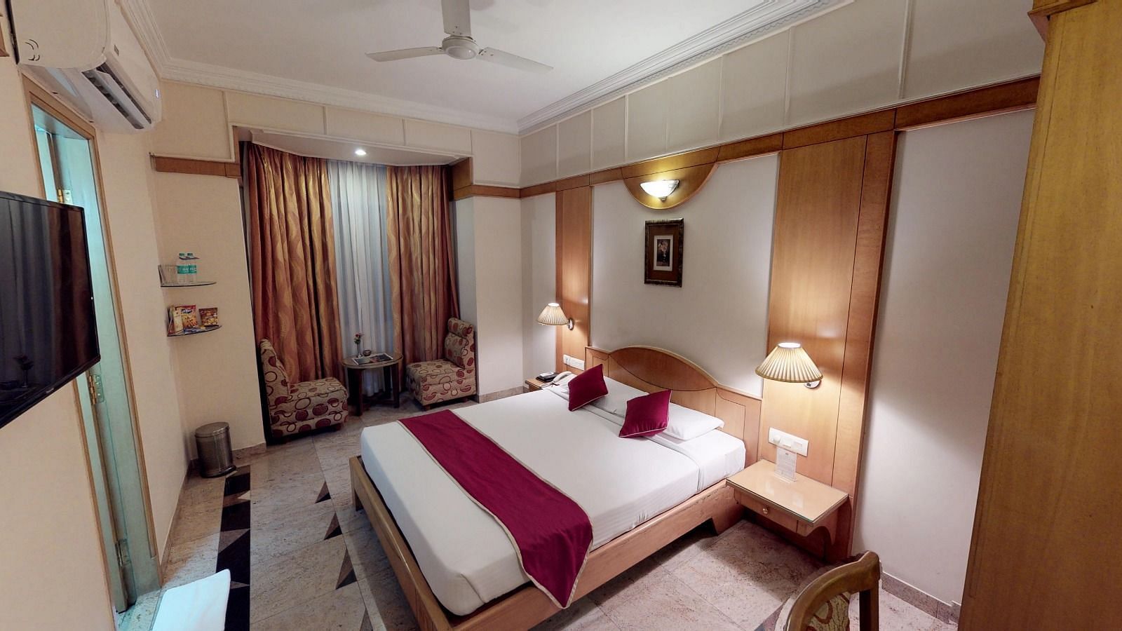 End to end view of the superior room at Hotel Pai Viceroy Jayanagar featuring a queen size bed, a television and a seating area with coffee table amongst other amenities