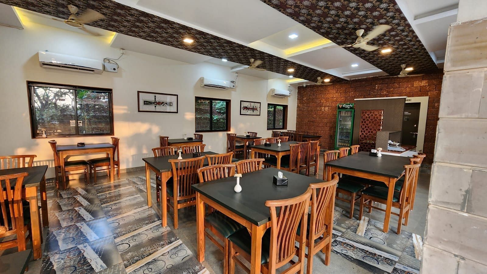 A diagonal view of the restaurant with wooden tables and chairs arranged neatly, and tables set for the guests at SeaFort Beach Resort