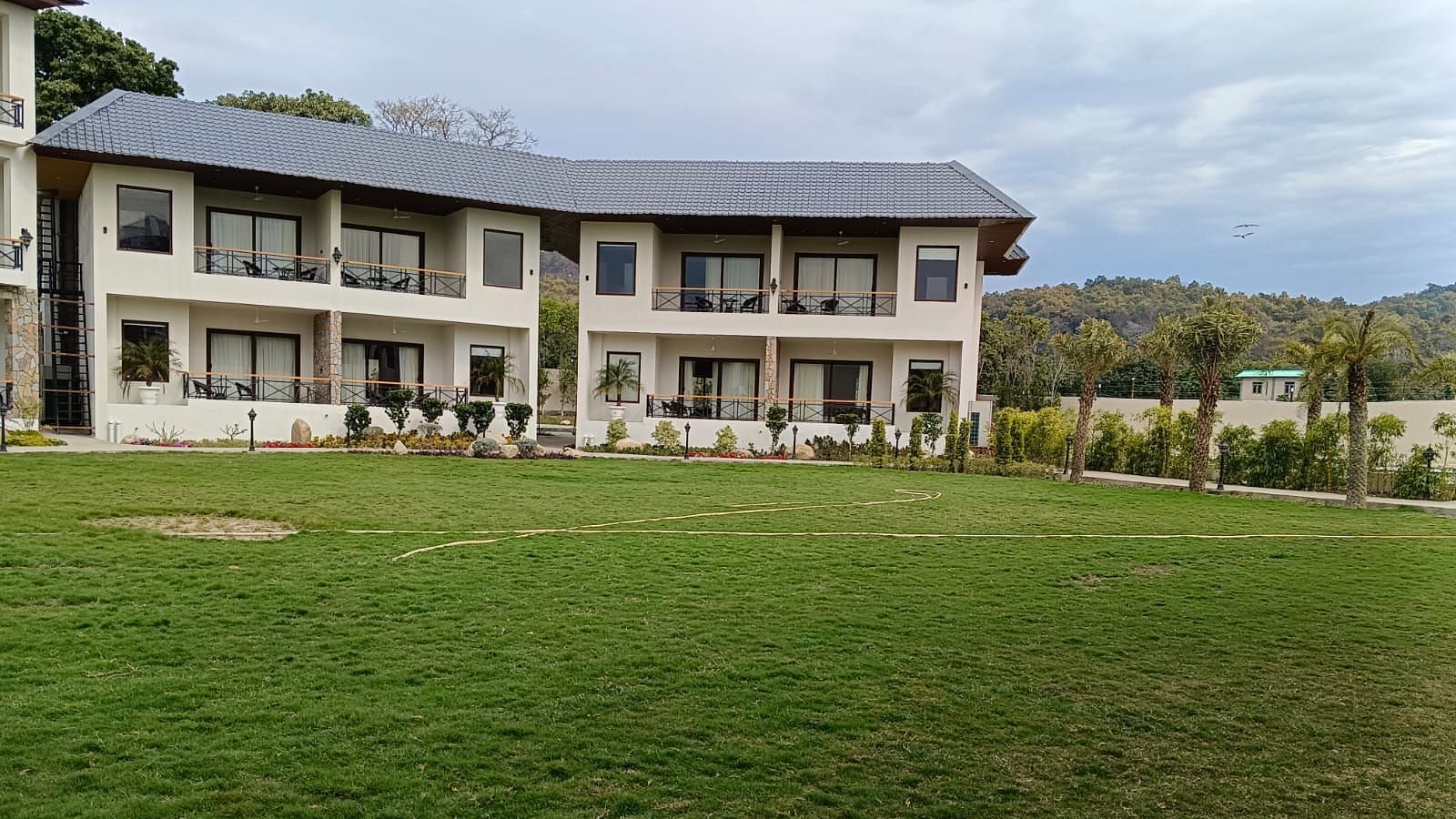 Lawn view of a two-story resort building with a grey roof and balconies - Pebbles & Pines, Corbett