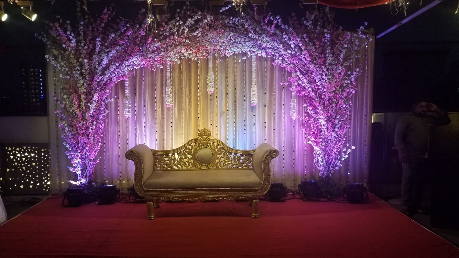 Image of a stage with a sofa and a backdrop of plants and lights at The Oriental Residency