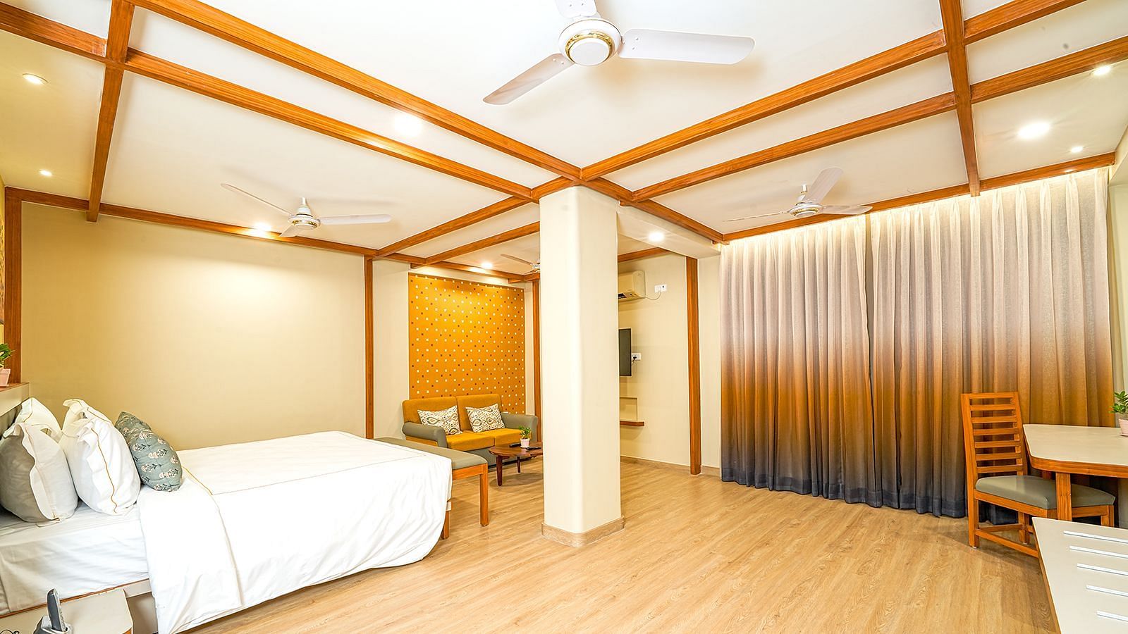 Spacious suite at Vasundhara Villa, Ramoji Film City featuring a cozy bed, stylish wooden interiors, and ample seating area for a relaxing stay.