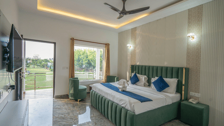 Full view of the Premium Room at Corbett Holiday Forest Resort, Ramnagar, with ample of natural light coming from the outside highlighting the double bed under the false ceiling.