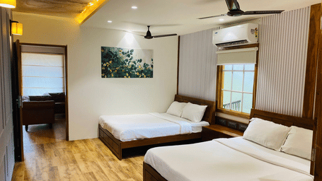 Spacious resort room with multiple beds and an integrated living area with comfortable seating - DAN Resorts & Weddings, Palghar