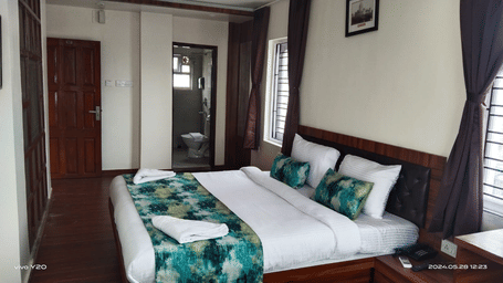 A double bed with towels kept on it inside the Deluxe room